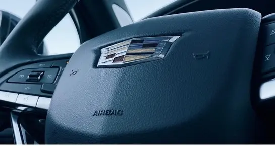 Close-up of the Cadillac emblem on a premium leather steering wheel