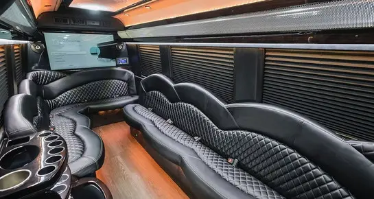 Custom Mercedes Sprinter Limo Van interior with plush perimeter seating, ambient mood lighting, and high-definition entertainment screens