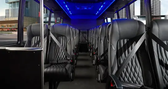Executive Mini Coach cabin with modern blue LED accent lighting and plush diamond-stitched seating for a luxury atmosphere
