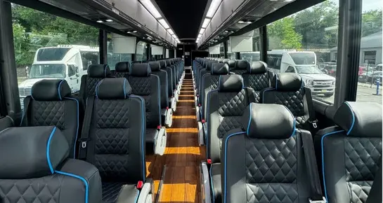 Luxury 56-passenger Motor Coach cabin with premium diamond-stitched leather seats, hardwood-style flooring, and climate control