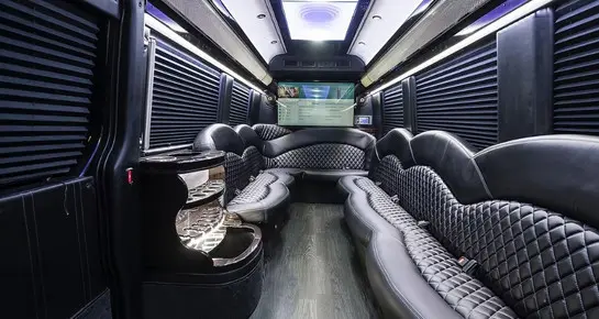 Luxury Sprinter Limo interior featuring diamond-stitched leather seating, hardwood flooring, and an integrated bar for premium group travel