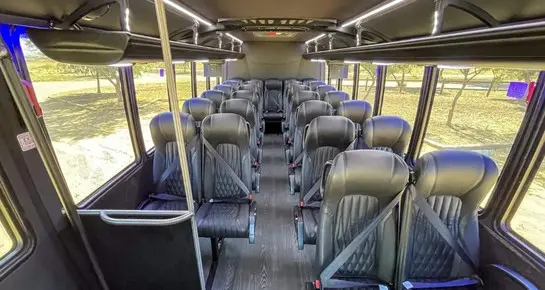 Premium mini coach interior with wood-style flooring, high-back leather seats, and integrated safety belts