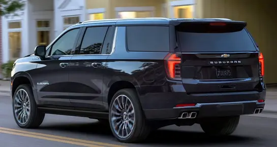 Rear exterior of a black Chevrolet Suburban executive SUV on a city street for livery service