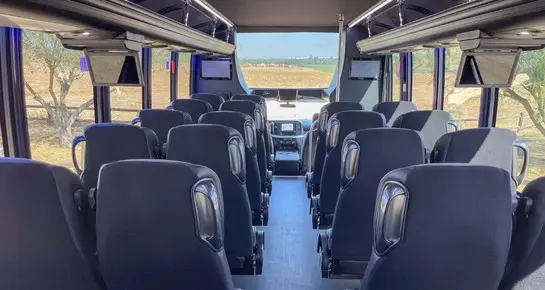 Spacious cabin of a luxury mini bus with forward-facing seating and panoramic windows for sightseeing and group travel