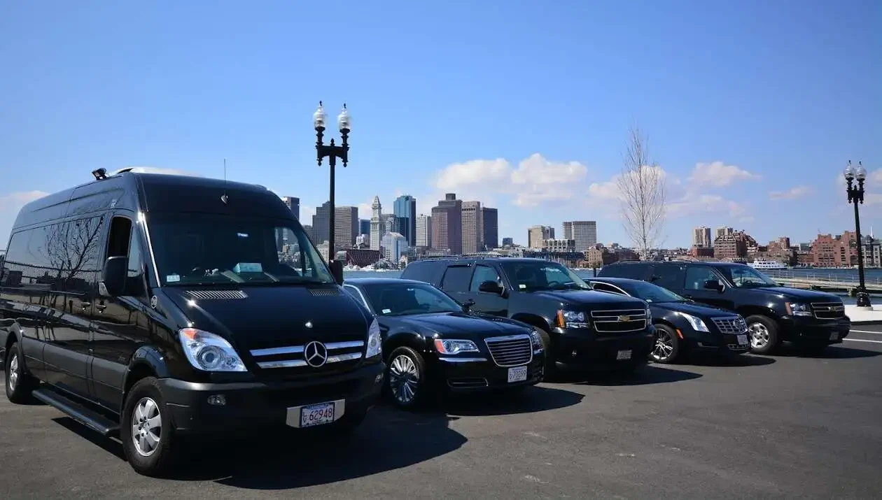 black luxury vehicles parked near waterfront with boston city skyline