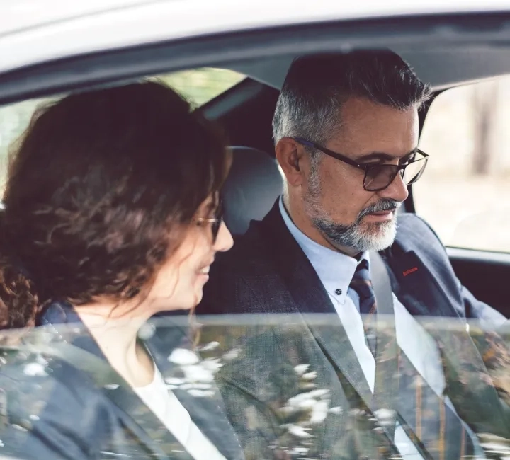 business man and woman in suits sitting inside a car